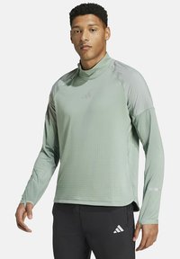 Lichtgroen atletisch shirt met lange mouwen en een opstaande kraag, van textuurstof met contrasterende grijze schouderpanelen. Adidas-logo op de borst.