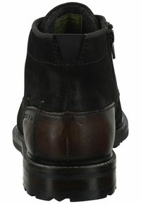 Sort læder ankelstøvle med en brun læderhæl accent, rund tå, sidelukning med lynlås og en struktureret sål.