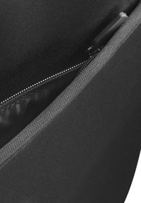 Nahaufnahme eines teilweise geöffneten schwarzen Reißverschlusses auf dunklem Stoff mit grauem gewebtem Saum entlang der Kante.