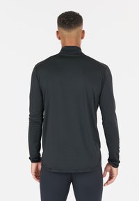 Svart l�ångärmad träningströja med hög krage, texturerat tyg och figurnära design. Har tumhål vid ärmsluten och rundad nederkant.