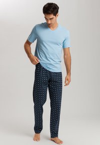 Jasnoniebieska koszulka typu v-neck w połączeniu z ciemnoniebieskimi spodniami dresowymi z geometrycznym wzorem w jasnym niebieskim kolorze. Miękka tkanina, luźny krój.