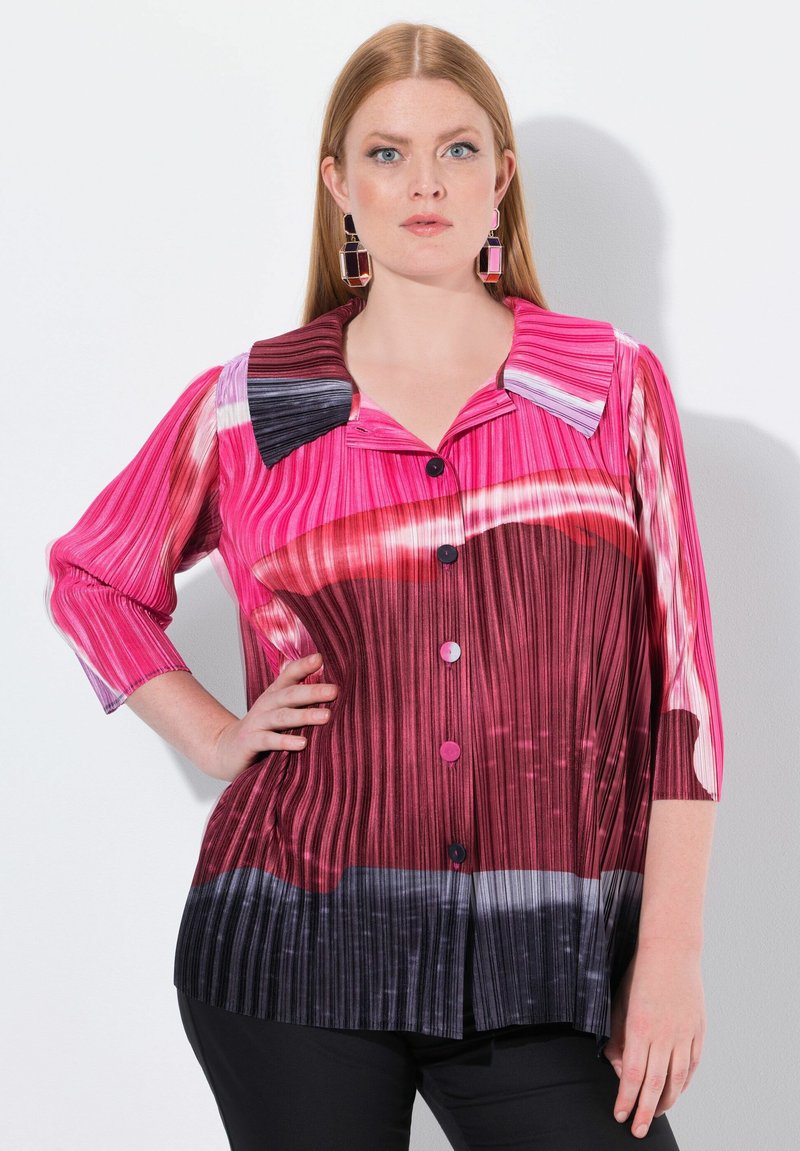 Blusa a righe rosa e rossa con colletto, chiusura a bottoni e maniche a tre quarti, con un motivo sfumato che transita verso tonalità scure.