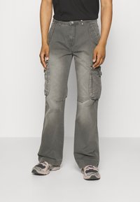 Graue Cargo-Hosen mit ausgestelltem Schnitt, großen seitlichen Taschen, Knopfleiste und kontrastierender Naht. Strukturierter Baumwollstoff.