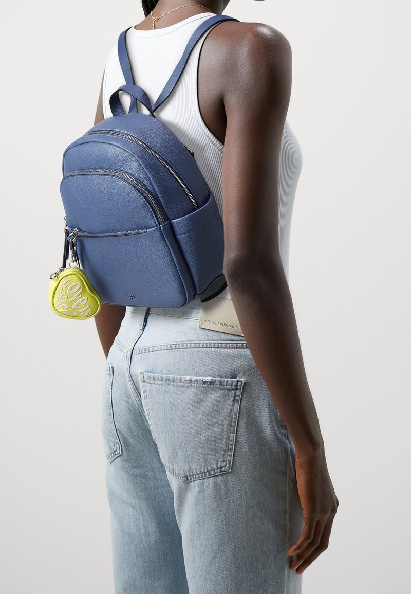 Zaino in pelle blu con spallacci regolabili, dotato di due scomparti con zip e un portachiavi a forma di cuore giallo attaccato.