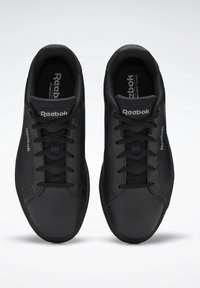 Black athletic sneakers feature a smooth leather upper, contrasting textured mesh tongue, black laces, and Reebok branding.