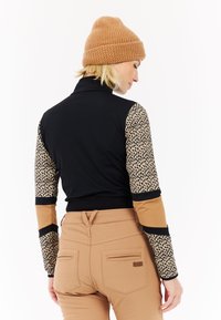 Zwart en luipaardprint lang mouwen top met een hoge kraag, gecombineerd met tan broek met twee achterzakken en een klein merketiket.