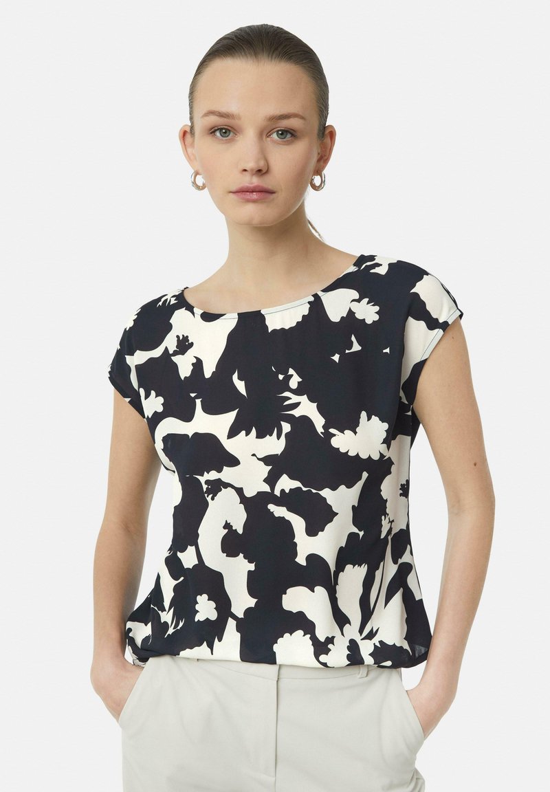 Short-sleeve top with a black and white floral pattern, crafted from lightweight fabric. Features a round neckline and relaxed fit.