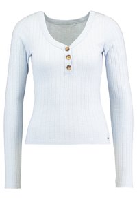 Ljusblå ribbad långärmad topp med V-ringning och tre träknappar framtill. Sömlös design, mjuk textur, figurnära siluett.