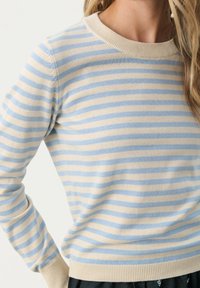 Pull rayé crème et bleu clair avec un col rond, des poignets et un ourlet côtelés, fabriqué en matière tricotée douce, présentant des rayures verticales.