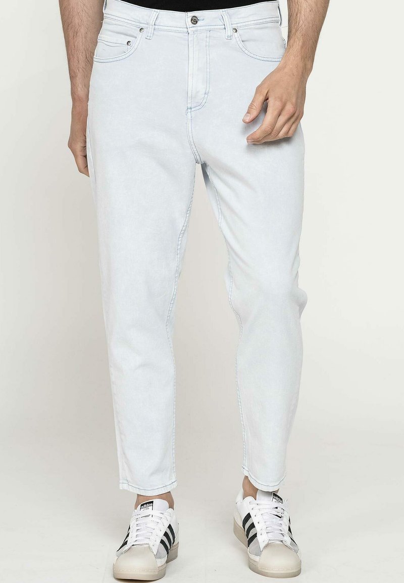 Jeans in denim blu chiaro con una vestibilità slim e una caviglia leggermente affusolata. Presenta un classico styling a cinque tasche e dettagli in hardware argentato.