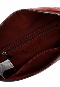 Punase nahast koti sisemus lukuvaruga tasku, kangast vooder ja hooldusjuhiste silt avatud luku taskus nähtaval.