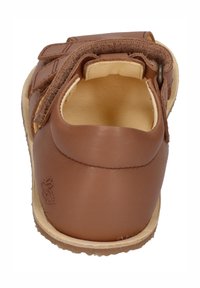 Braune Leder-Sandale mit geschlossenem Fersenbereich, verstellbarem Riemen und beiger Laufsohle. Glatte Oberfläche mit einfachem Design und Nähedetails.