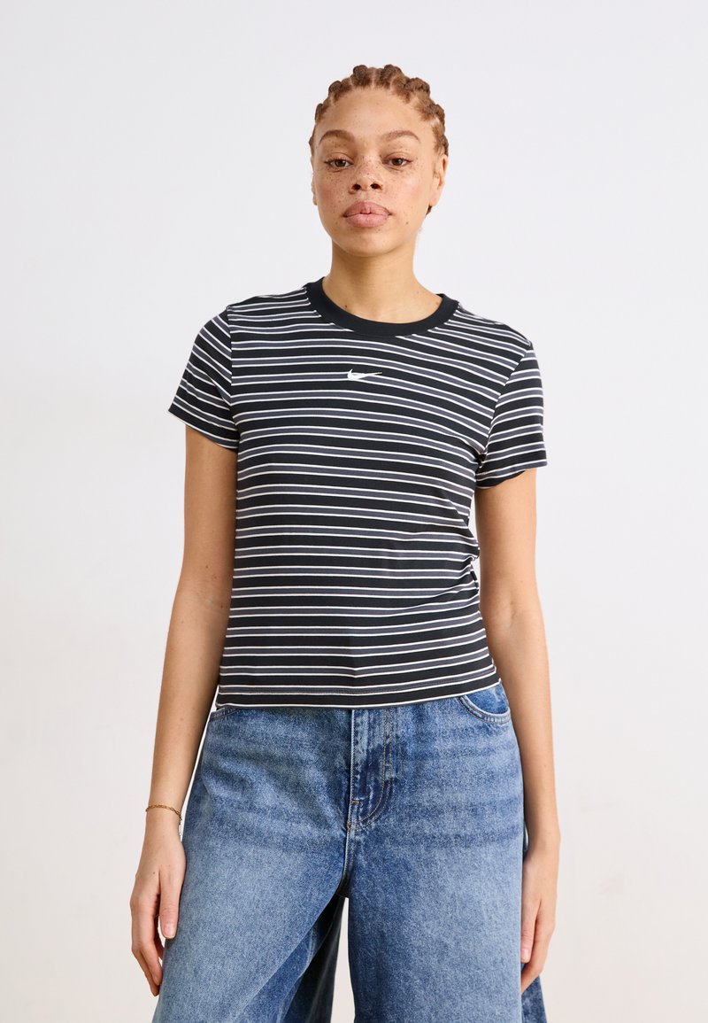 Μαύρο και λευκό ριγέ T-shirt με στρογγυλή λαιμόκοψη και κοντά μανίκια, που διαθέτει ένα μικρό λογότυπο της Nike στο στήθος. Συνδυασμένο με μπλε τζιν.