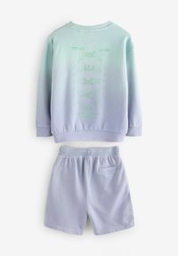 Felpa blu chiaro e pantaloncini abbinati. La felpa presenta un design a gradiente con un logo grafico verde. Texture liscia, vestibilità casual.