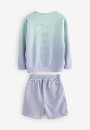 Světle modrá mikina a odpovídající šortky. Mikina má gradientní design se zeleným grafickým logem. Hladká textura, volný střih.