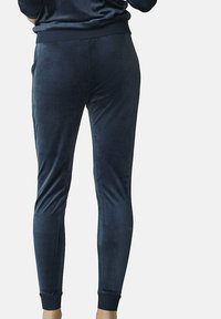 Joggers en velours bleu marine au design fuselé, avec des poignets côtelés aux chevilles et une texture lisse. Idéaux pour une tenue décontractée ou pour se détendre.