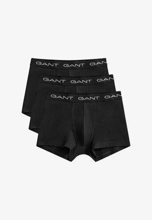 Trois boxers noirs pour hommes avec taille élastique portant le logo blanc "GANT", soigneusement empilés sur un fond blanc.