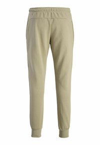 Light beige joggers with an elastic waistband, side pockets, and tapered cuffs. Made from soft, stretchable fabric.