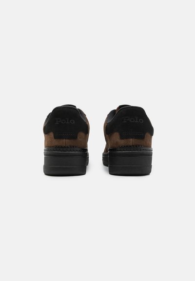 Bruine suède sneakers met zwarte accenten, voorzien van een gestructureerde zool en een geperst logo op de hiel, ontworpen voor casual gebruik.