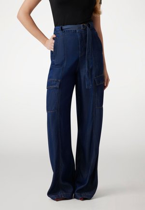 Pantalones cargo de pierna ancha en denim oscuro con una cintura alta, trabillas, pockets laterales y detalles de costura visibles. Textura suave.