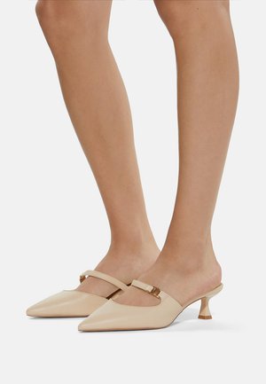 Beige leather mules with a pointed toe, featuring a single strap and a small, curved heel. Smooth texture with subtle shine.