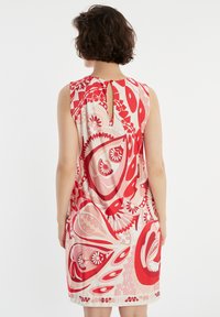 Une robe sans manches de longueur genou avec un motif floral abstrait coloré en rouge et rose, dotée d'un détail en forme de trou de serrure à l'arrière.