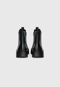Zwarte leren enkellaarzen met een gladde afwerking, voorzien van zijritsen en een gestructureerde rubberen zool, ontworpen met een minimalistische esthetiek.