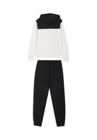Felpa con cappuccio con sezione superiore nera e inferiore crema, abbinata a pantaloni della tuta neri. Entrambi realizzati in tessuto morbido, con polsini a coste.