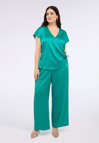 Sytě tyrkysový saténový top s výstřihem do V a krátkými rukávy, doplněný širokými kalhotami. Texturovaná látka s akcentem na bocích a šňůrkou.