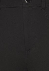 Svarta byxor med en slät yta, som har en knappstängning och subtila sömnadsdetaljer. Inkluderar sidfickor och en figurnära design.