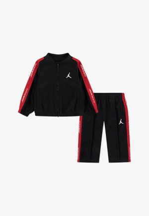 Black tracksuit featuring a zip-up jacket with red stripes, "JORDAN" text, and logo. Matching pants with elastic waistband and side stripes.