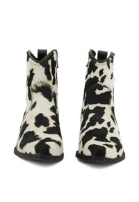 Stivaletti in pelle di mucca con un motivo patchwork bianco e nero, punta affusolata, tacco basso e suola in gomma nera a contrasto.