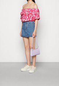 Haut rose à fleurs à manches dénudées avec des volants, mini-jupe en denim bleu, sac à main violet clair et baskets à plateforme beige.