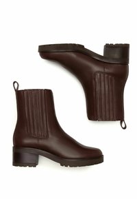 Botas de tobillo de cuero marrón oscuro con tacones de bloque, paneles laterales elásticos, tiradores y suelas de perfil rugoso, mostradas en vistas lateral y inferior.