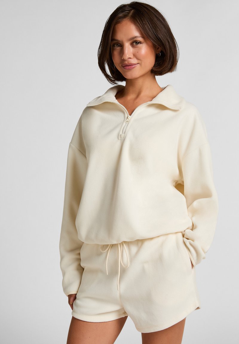 Set van crème-kleurig sweatshirt en korte broek in zachte stof. Het sweatshirt heeft een halve rits en een losse pasvorm; de korte broek heeft een elastische tailleband.