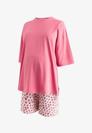 Laza pink rövid ujjú felső fehér rövidnadrággal, melyeken rózsaszín és piros szívminta található.