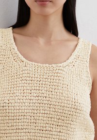 Gebreide tanktop in romig beige met een losse haakontwerp, met een brede, ronde halslijn en fijne, gestructureerde details.