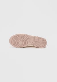 Outsole Nike tenisky s textúrovanou gumou, s kruhovým vzorom a horizontálnymi drážkami, sfarbené do svetloružových a béžových odtieňov.