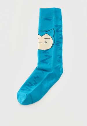 Calcetín de media caña de color turquesa con un gato de dibujos animados dormido y letras de color azul oscuro, sobre un fondo claro.