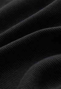 Tela negra acanalada, con una superficie texturizada que presenta líneas paralelas elevadas, creando una apariencia suave y ondulada a la luz natural.