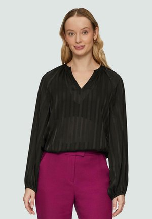 Schwarze Bluse mit vertikalen Streifen, V-Ausschnitt und langen Ärmeln. Kombiniert mit hoch taillierten fuchsiafarbenen Hosen, die einen maßgeschneiderten Schnitt haben.