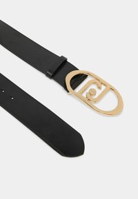 Zwarte leren riem met een grote, gouden ovalen gesp met overlappende vormen en logo-details. Gladde textuur en taps toelopende uiteinden.