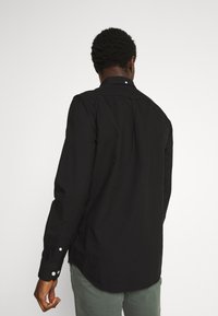 Black long-sleeve shirt with a pointed collar, buttoned cuffs, and a straight back design. Smooth fabric with a tailored fit.