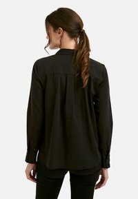 Black long-sleeve shirt with a collared neck, smooth texture, and buttoned cuffs; features a back pleat for added movement and comfort.