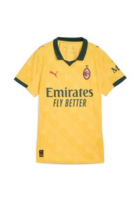 Žltý futbalový dres s krátkym rukávom a zeleným golierom a akcentmi. Obsahuje logo Puma a text "Emirates Fly Better". Textúra má vzorovaný dizajn.