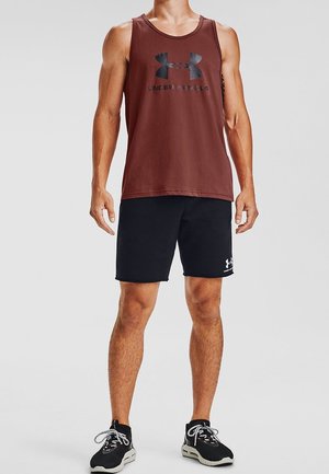 Czerwony bezrękawnik sportowy z czarnym logo, zestawiony z czarnymi szortami z białym logo, noszonymi z czarnymi butami sportowymi.