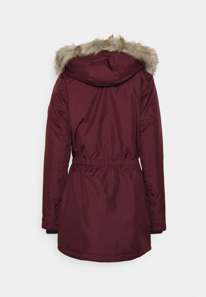 Parka bordeaux avec une bordure de capuche en fausse fourrure, taille cintrée et manches longues. Tissu lisse et résistant à l'eau avec des accents de poignet noirs.