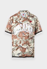Πουκάμισο με κοντό μανίκι και κουμπιά, με μοτίβο καμουφλάζ σε μπεζ, καφέ και ταμπά αποχρώσεις και μεγάλο λευκό κείμενο "ICECREAM" στο μπροστινό μέρος.