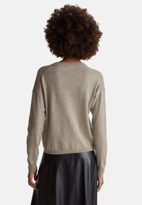 Jasnoszary sweter dzianinowy o luźnym kroju, z prążkowanym dekoltem i długimi rękawami. Miękka faktura, casualowy design i lekko skrócony dół.