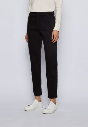 Zwarte katoenen broek in een slim fit, met voorzakken, riemlussen en een gladde textuur, gecombineerd met witte sneakers.